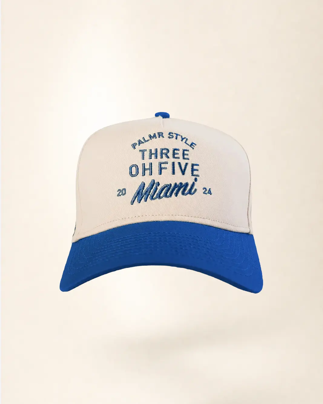 A white and blue baseball cap with embroidered text reading 'PALMR STYLE THREE OH FIVE 20 Miami 26' on the front, shown against a plain cream background.
