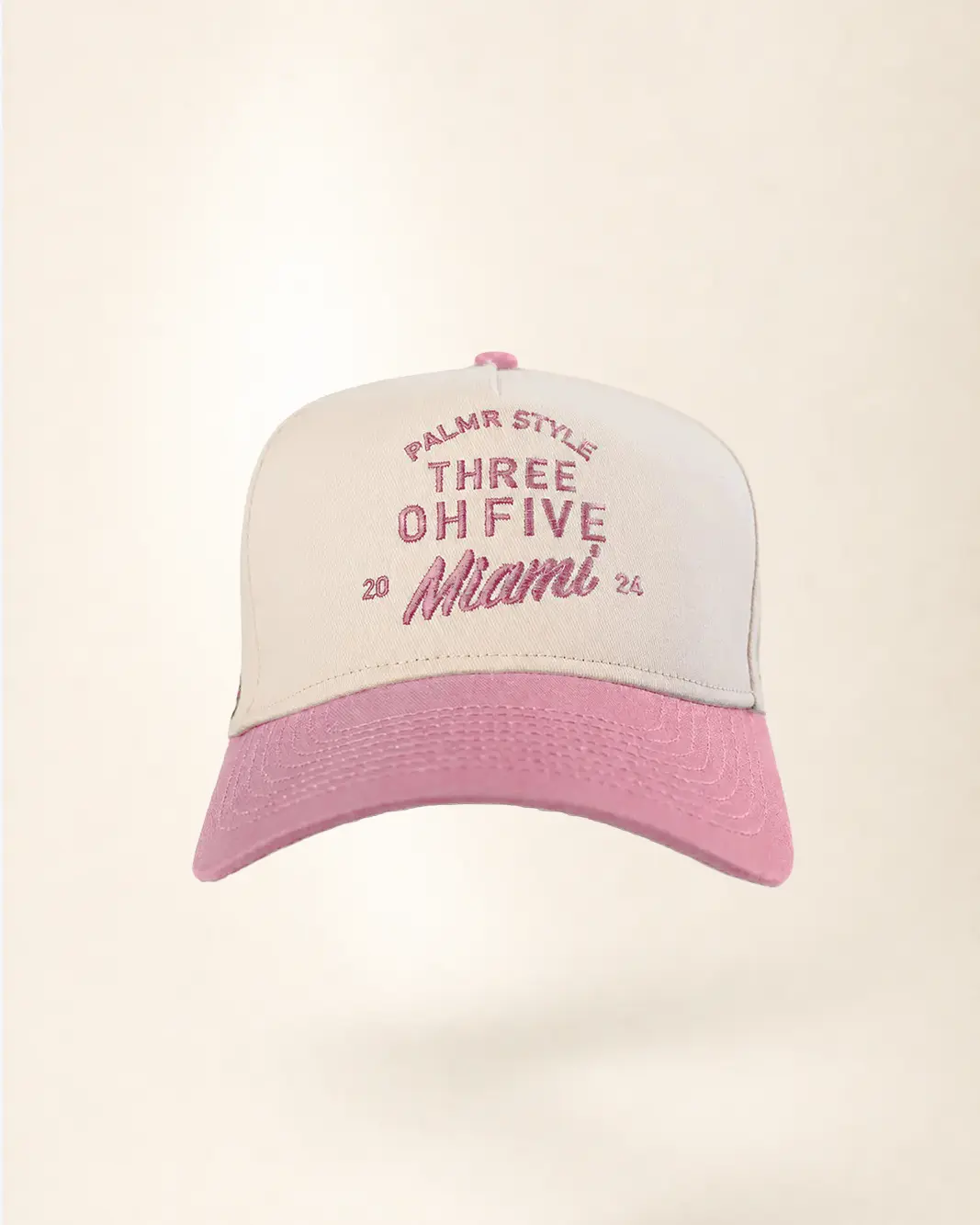 A pink and white trucker-style baseball cap with embroidered text reading 'PALM STYLE THREE OH FIVE Miami 20' on the front panel, shown against a plain light beige background.