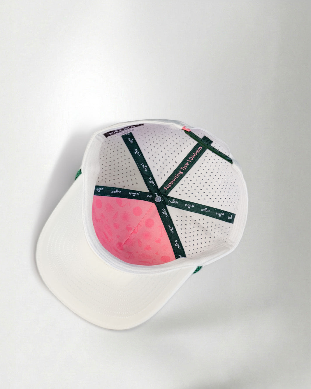 White baseball cap with pink interior and black branding on a white background
