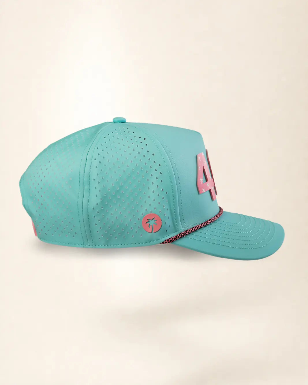 A turquoise mesh baseball cap with pink accents, including a large '4' on the side and a small circular palm tree logo patch, shown against a plain beige background.