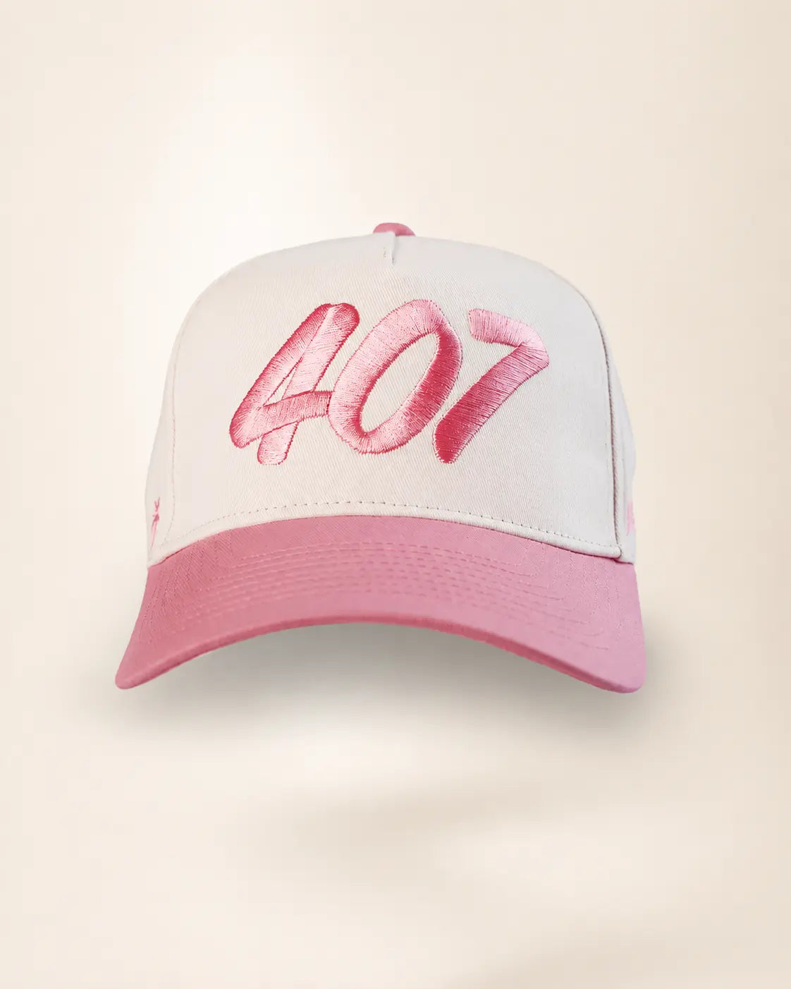 A baseball cap with a white crown, pink brim, and pink embroidered '407' text on the front, shown against a light beige background.