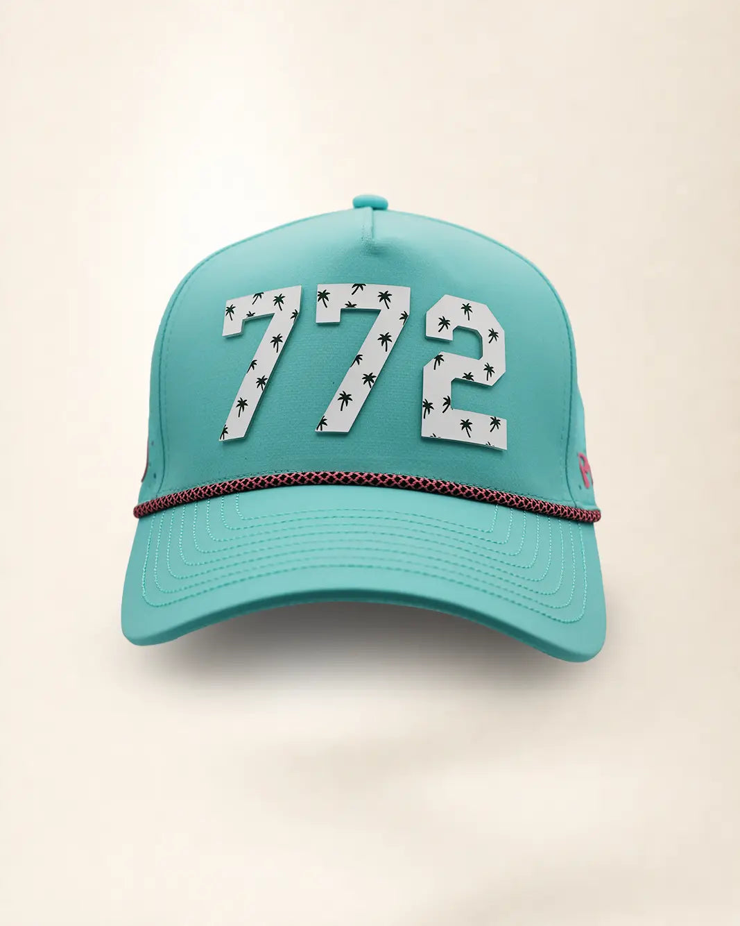 The 772 Signature Hat (Teal), front view: white raised 772 with small palm print on a teal crown, pink and black rope along the brim.