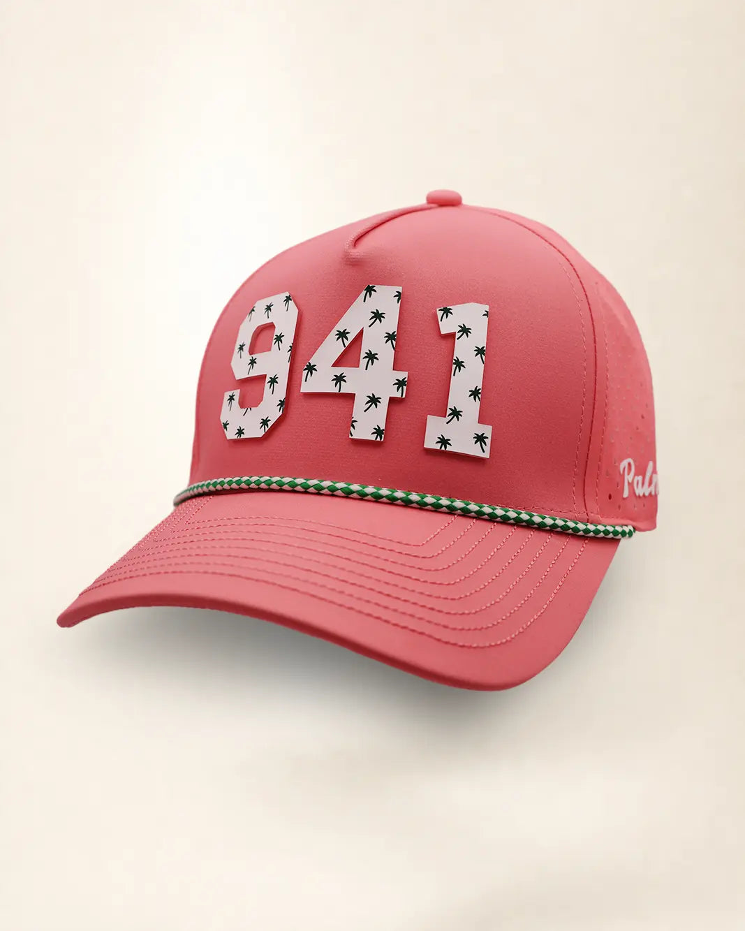 A pink perforated baseball cap showcasing the '941' with a green and white patterned trim along the brim and white 'Palmr' script embroidery on the side, shown against a light beige background.