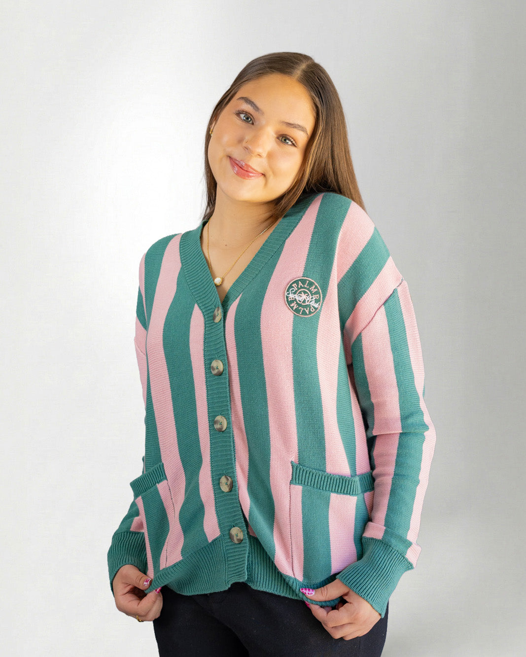 Woman wearing a green and pink striped cardigan on a white background