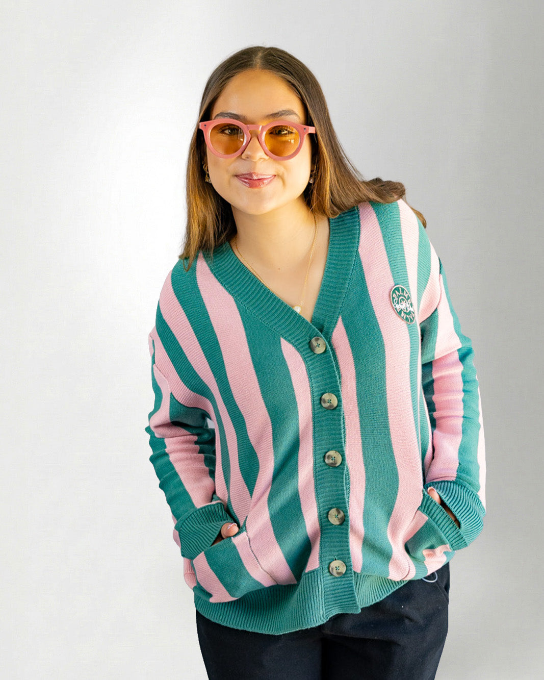Woman wearing a green and pink striped cardigan on a white background