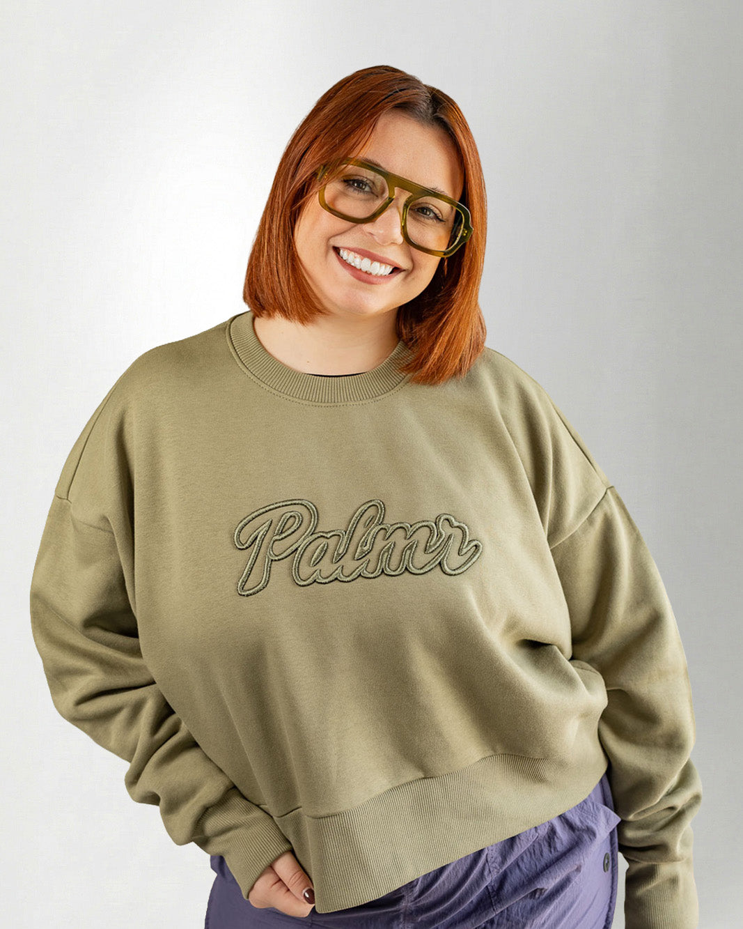 Person wearing a green sweatshirt with 'Palmr' text on a plain background