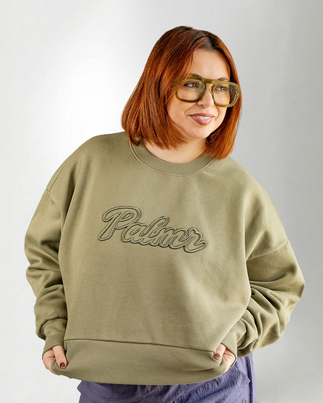 Person wearing a green sweatshirt with 'Palmr' text on a plain background