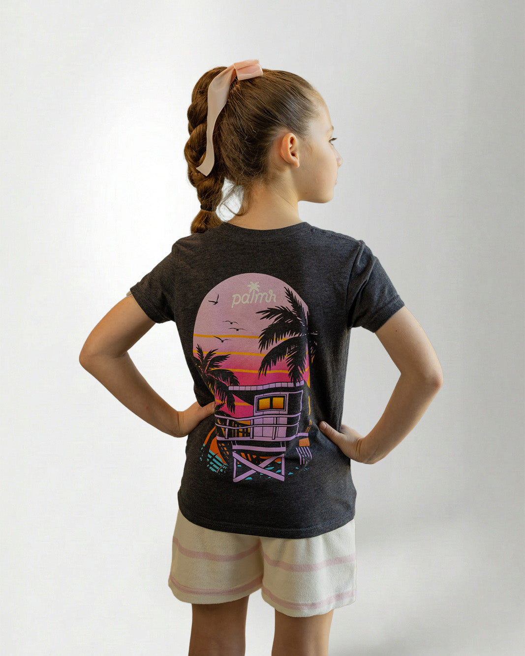 Child wearing a black t-shirt with a colorful graphic design on the back, standing against a plain background.