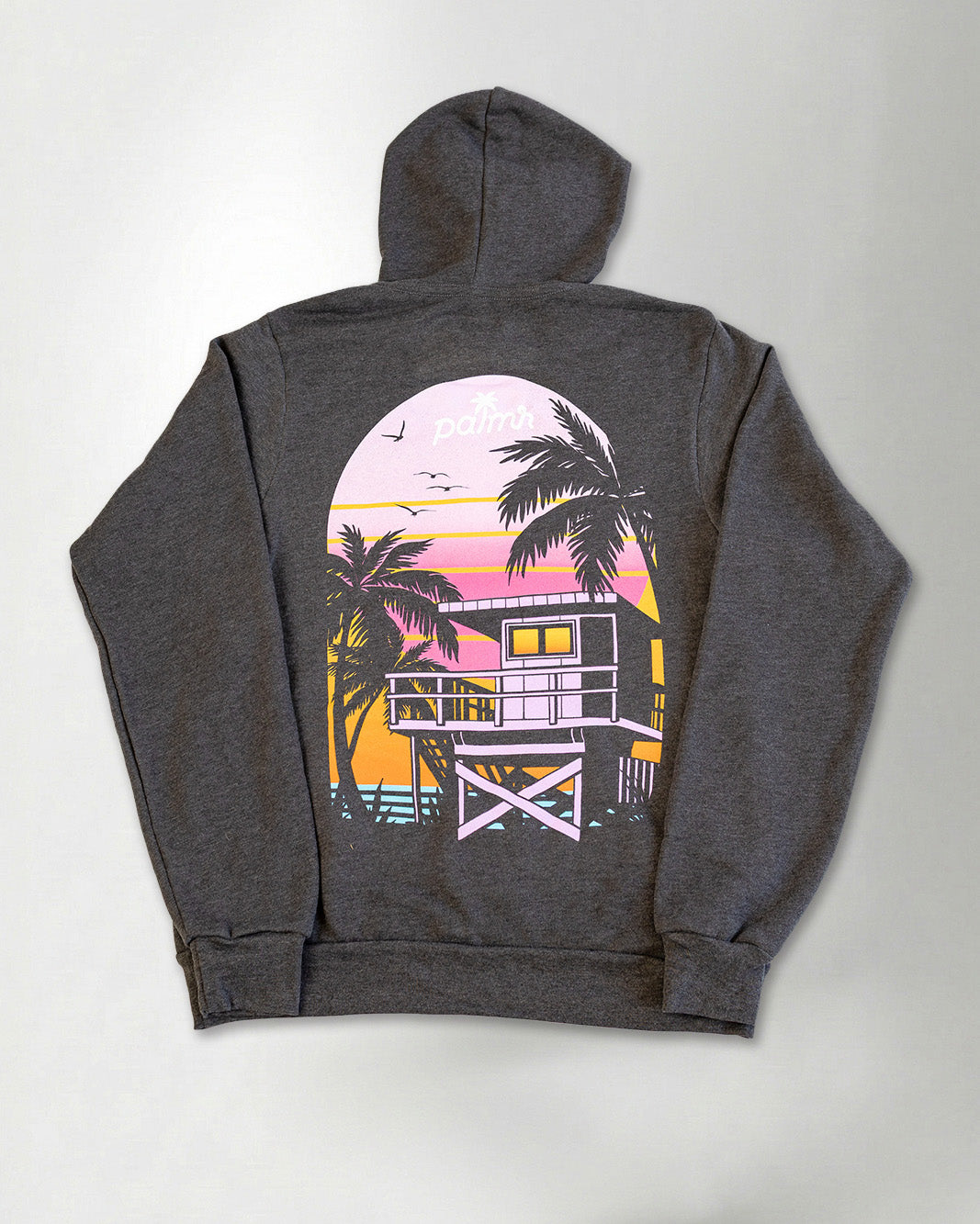 A hoodie with a sunset and palm tree design on the back against a plain background.