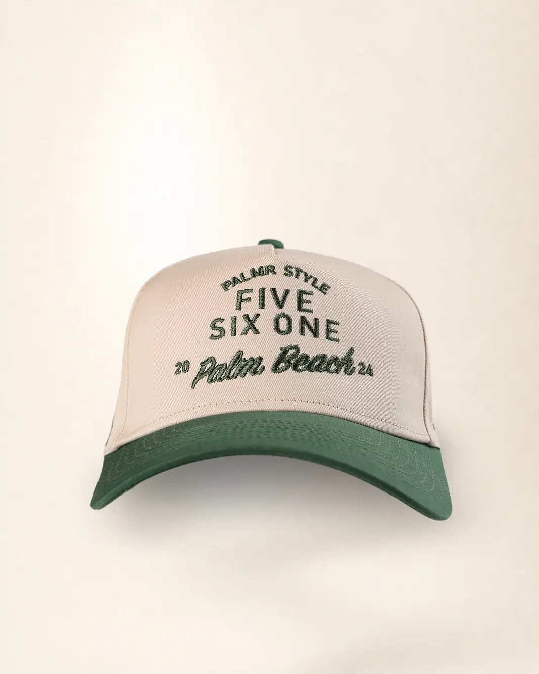 A structured trucker-style baseball cap with a cream-colored front panel and a dark green curved brim. The front panel features embroidered text reading 'PALMR STYLE FIVE SIX ONE 20 Palm Beach 25' in dark green.