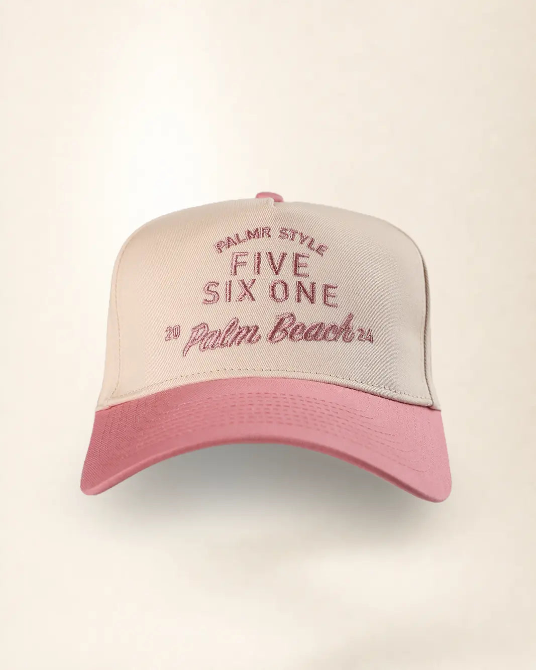A two-tone baseball cap with a light beige crown and a pink brim, featuring pink embroidered text that reads 'PALMR STYLE FIVE SIX ONE 2 Palm Beach 25'.