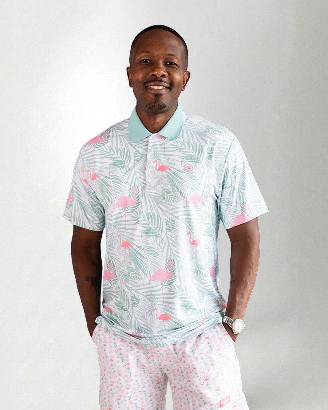 Man wearing a patterned shirt and pants against a plain background
