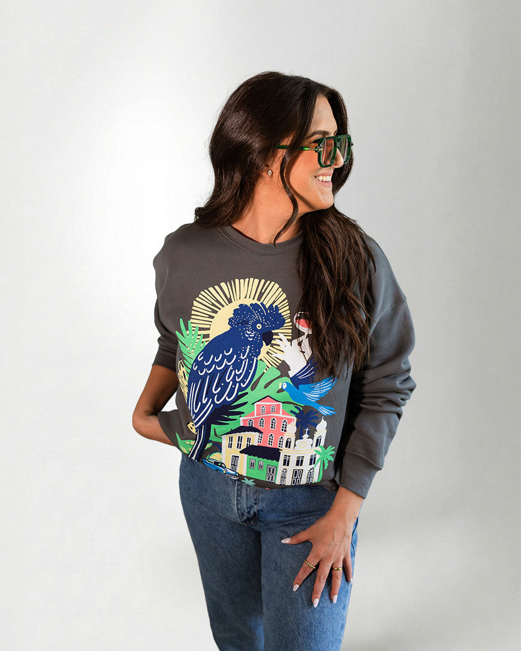 Woman wearing a sweatshirt with a colorful parrot design on a plain background