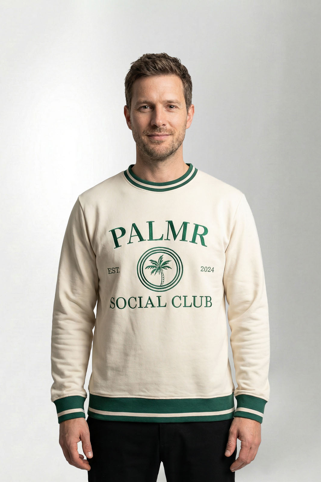 Man wearing a cream-colored sweatshirt with 'Palmr Social Club' branding on a light gray background