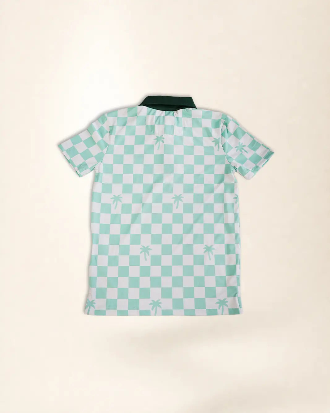 A short-sleeve polo shirt with a mint green and white checkerboard pattern and small palm tree motifs, laid flat on a light beige background.