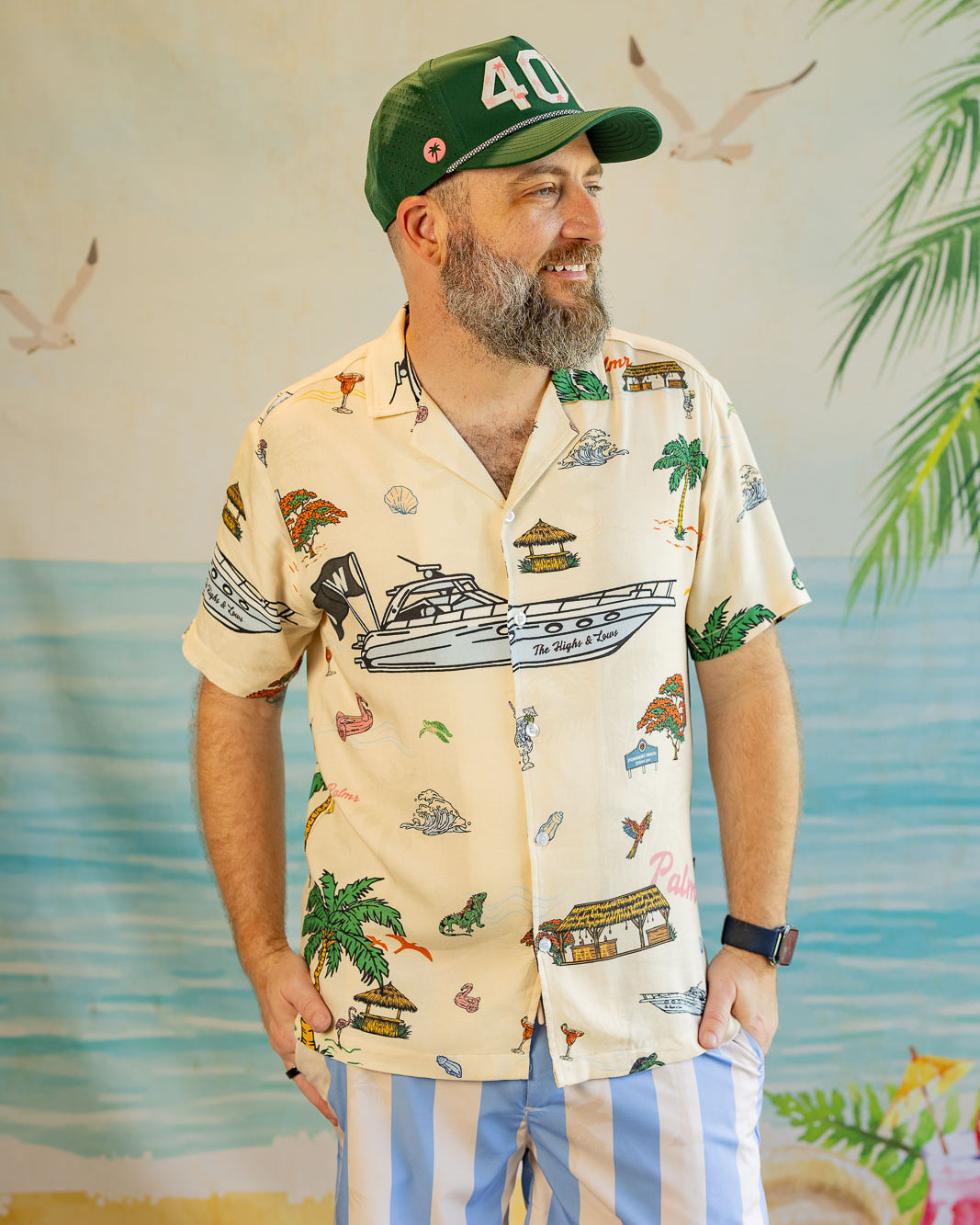 Man wearing a patterned shirt and cap with a tropical background