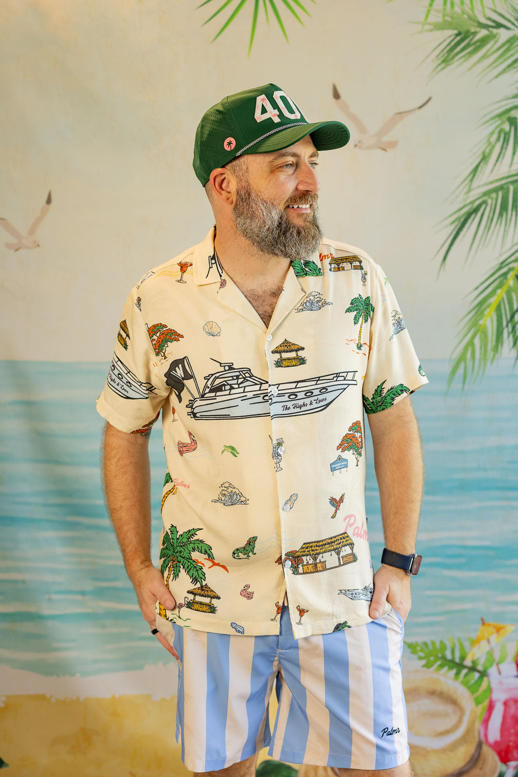 Man wearing a patterned shirt and cap with a tropical background
