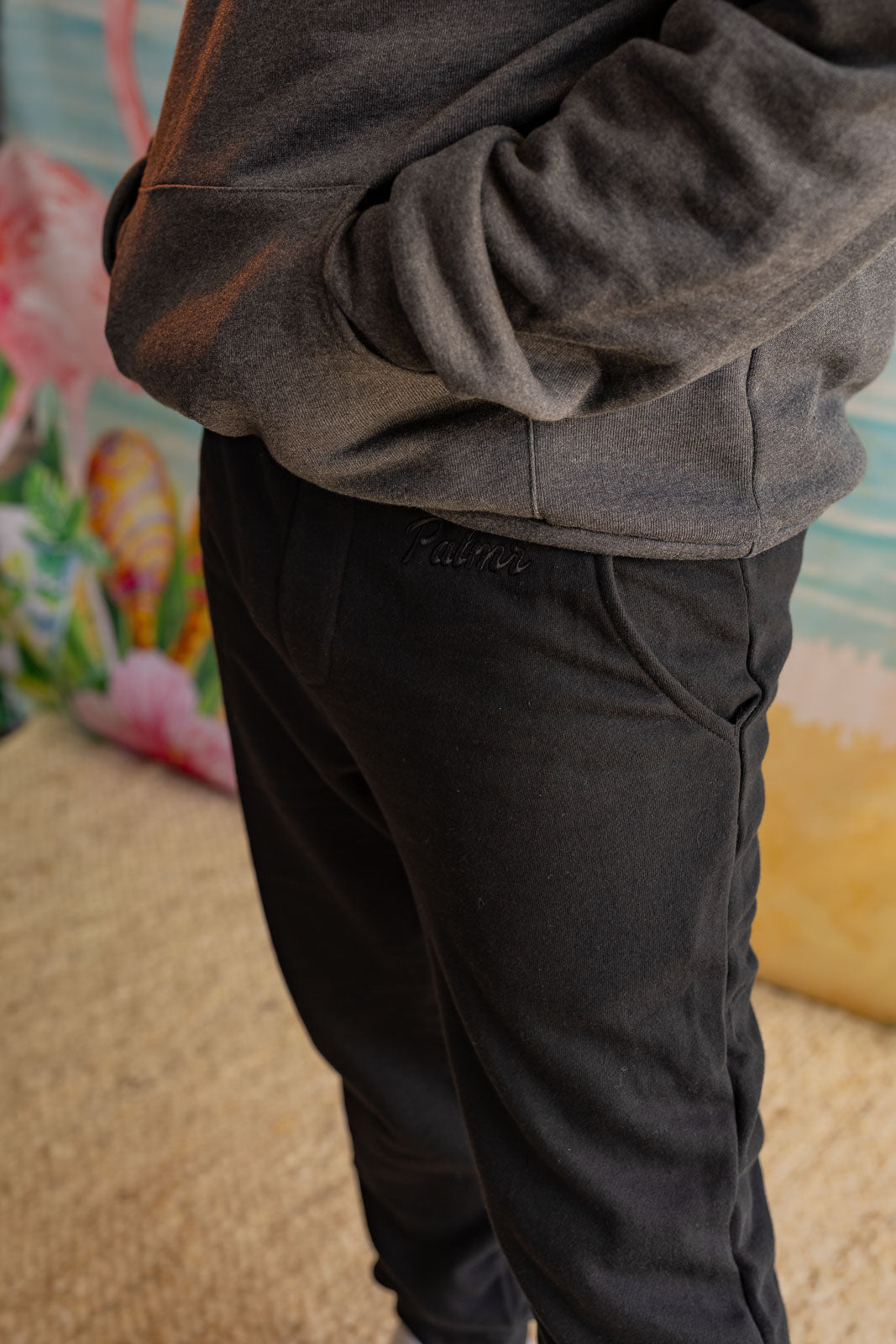 Person wearing a gray hoodie and black pants with a colorful background