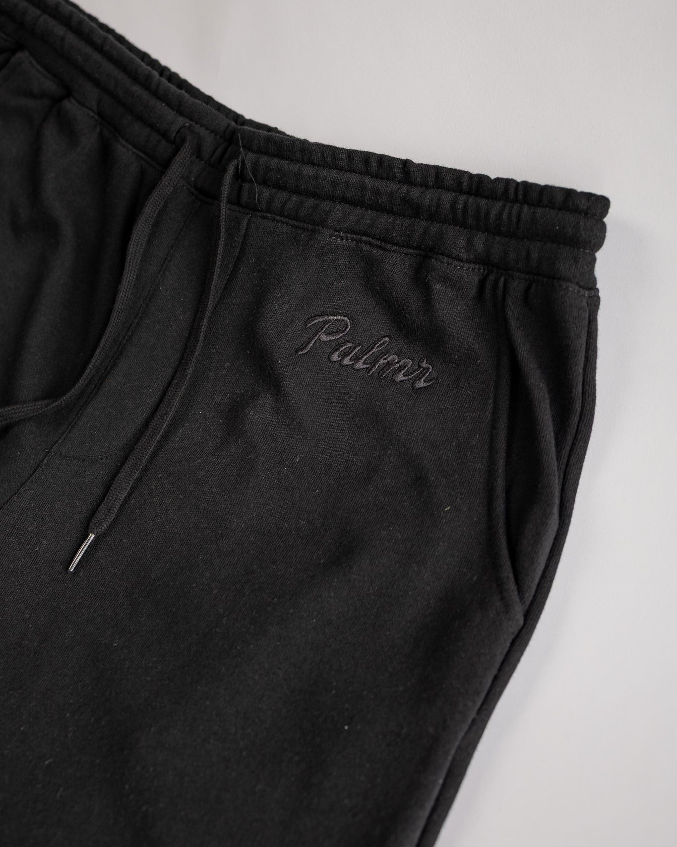 Black sweatpants with 'Palmr' embroidery on a light gray background
