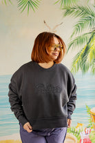 Person wearing a dark gray sweatshirt with 'Palmer' text, standing against a tropical-themed background.
