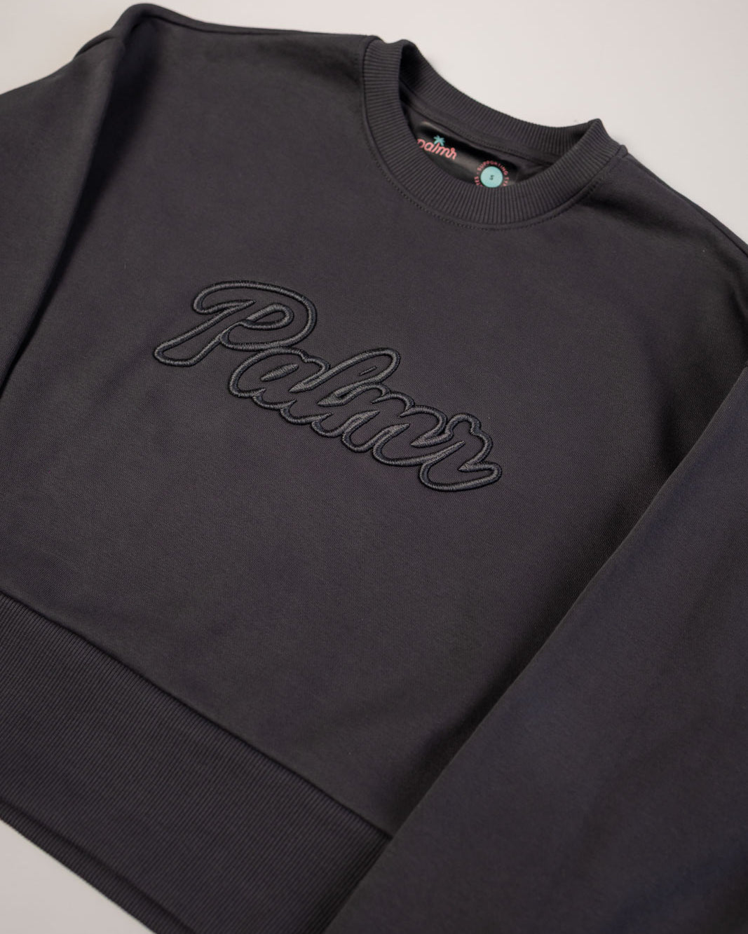 Black sweatshirt with 'Palace' branding on a light gray background