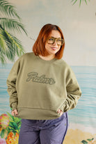 Person wearing a green sweatshirt with 'Palmer' text against a tropical-themed background