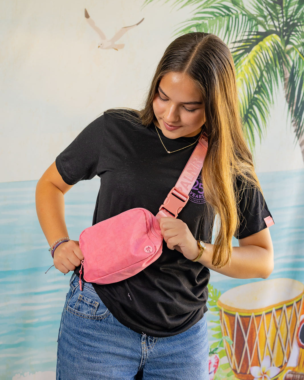 Woman wearing a pink fanny pack with a tropical background