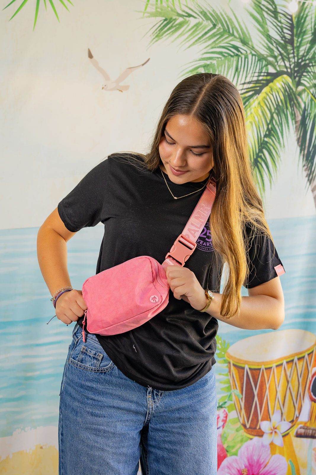 Woman wearing a pink fanny pack with a tropical background