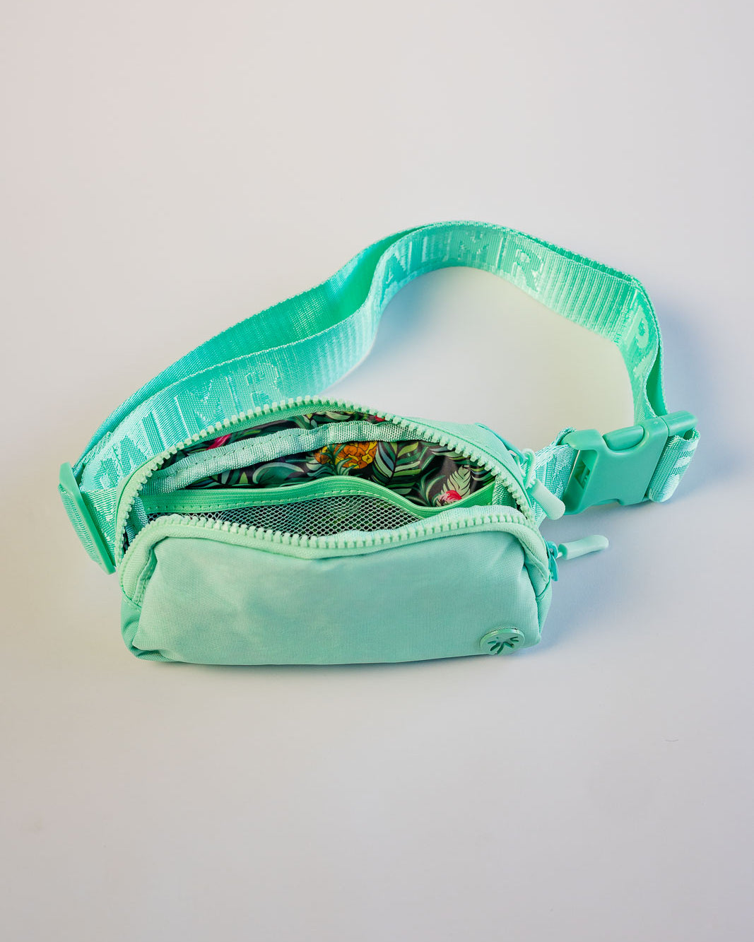 Turquoise waist bag with a clear compartment on a light gray background