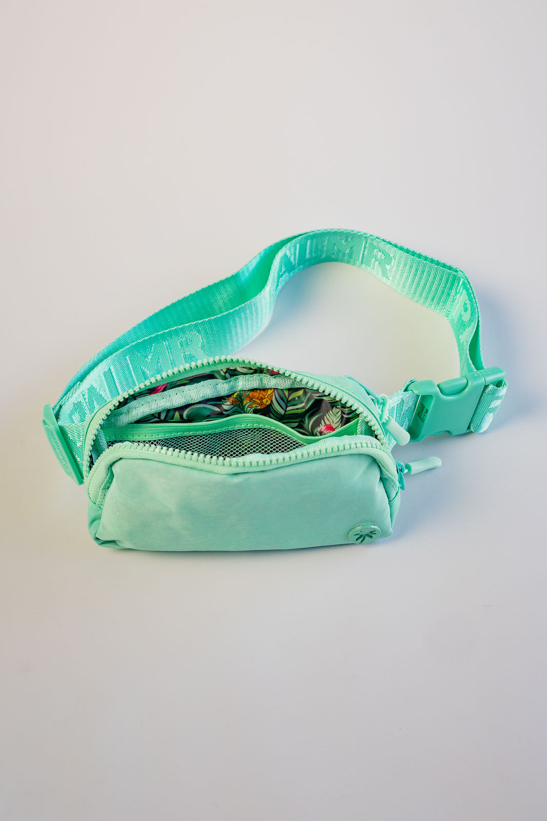 Turquoise waist bag with a clear compartment on a light gray background