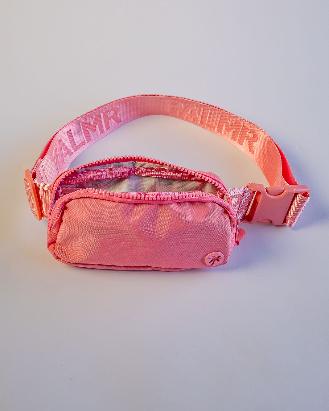 Pink waist bag with transparent front pocket on a light gray background