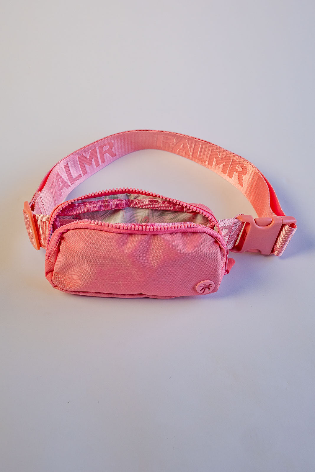 Pink waist bag with transparent front pocket on a light gray background