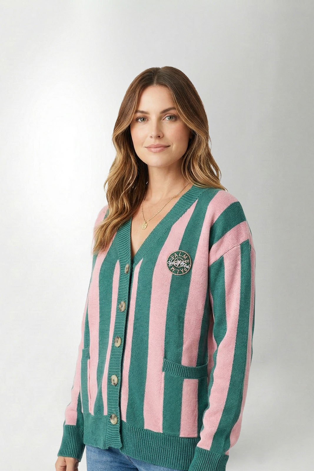 Woman wearing a green and pink striped cardigan on a white background