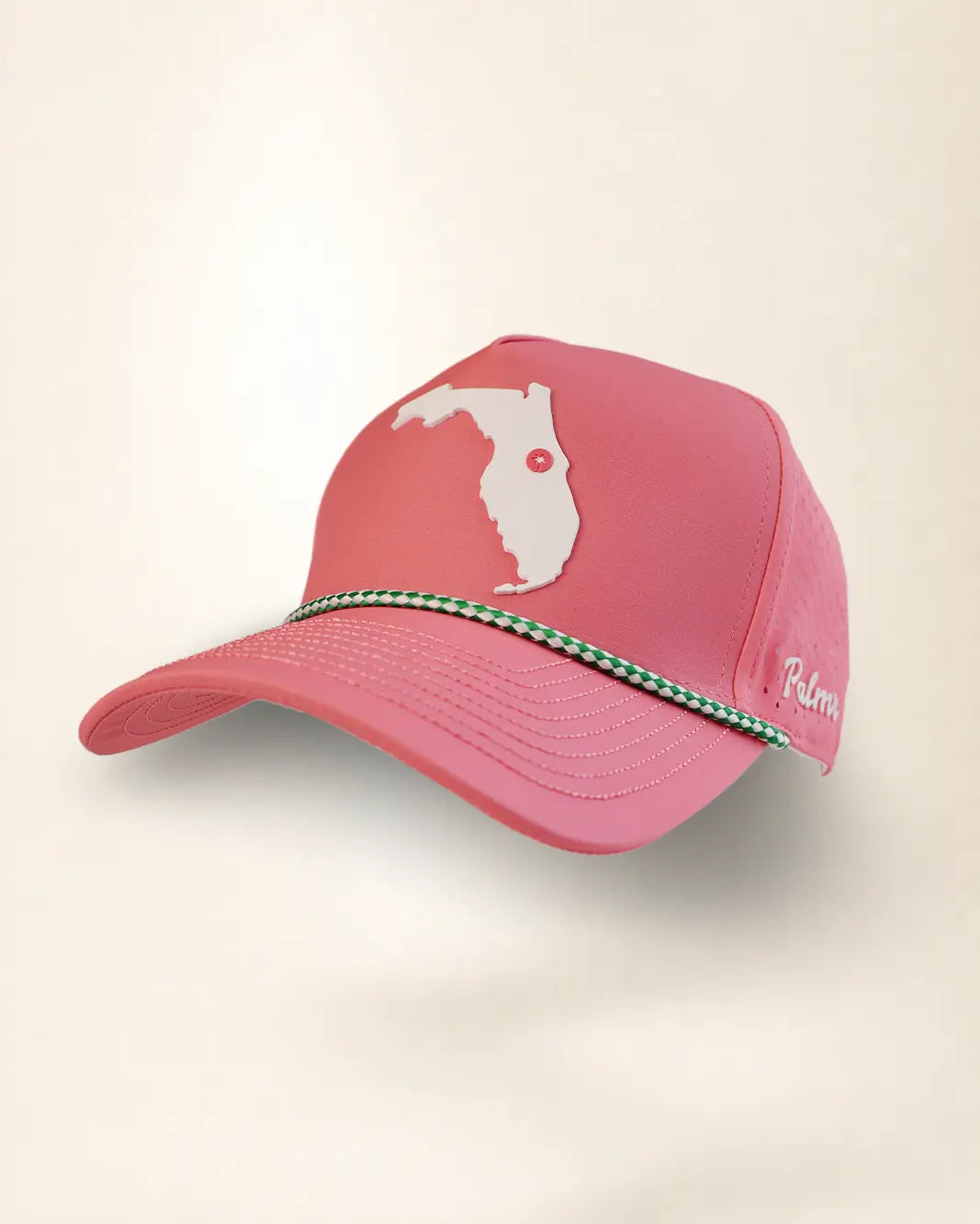 A pink baseball cap featuring a white Florida state silhouette graphic on the front, a green and white patterned decorative band across the brim, and white script embroidery on the side, shown against a plain light beige background.