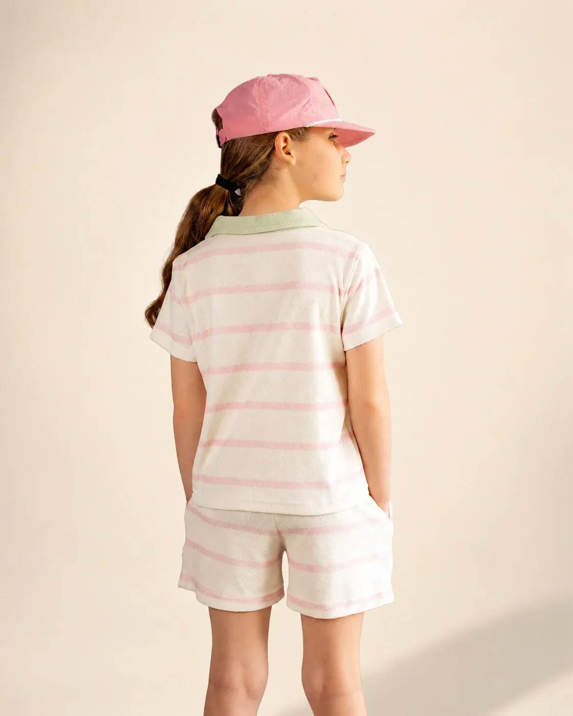 Girl wearing Cabana Pink Stripe top with green collar and pocket, styled for casual beach and pool days