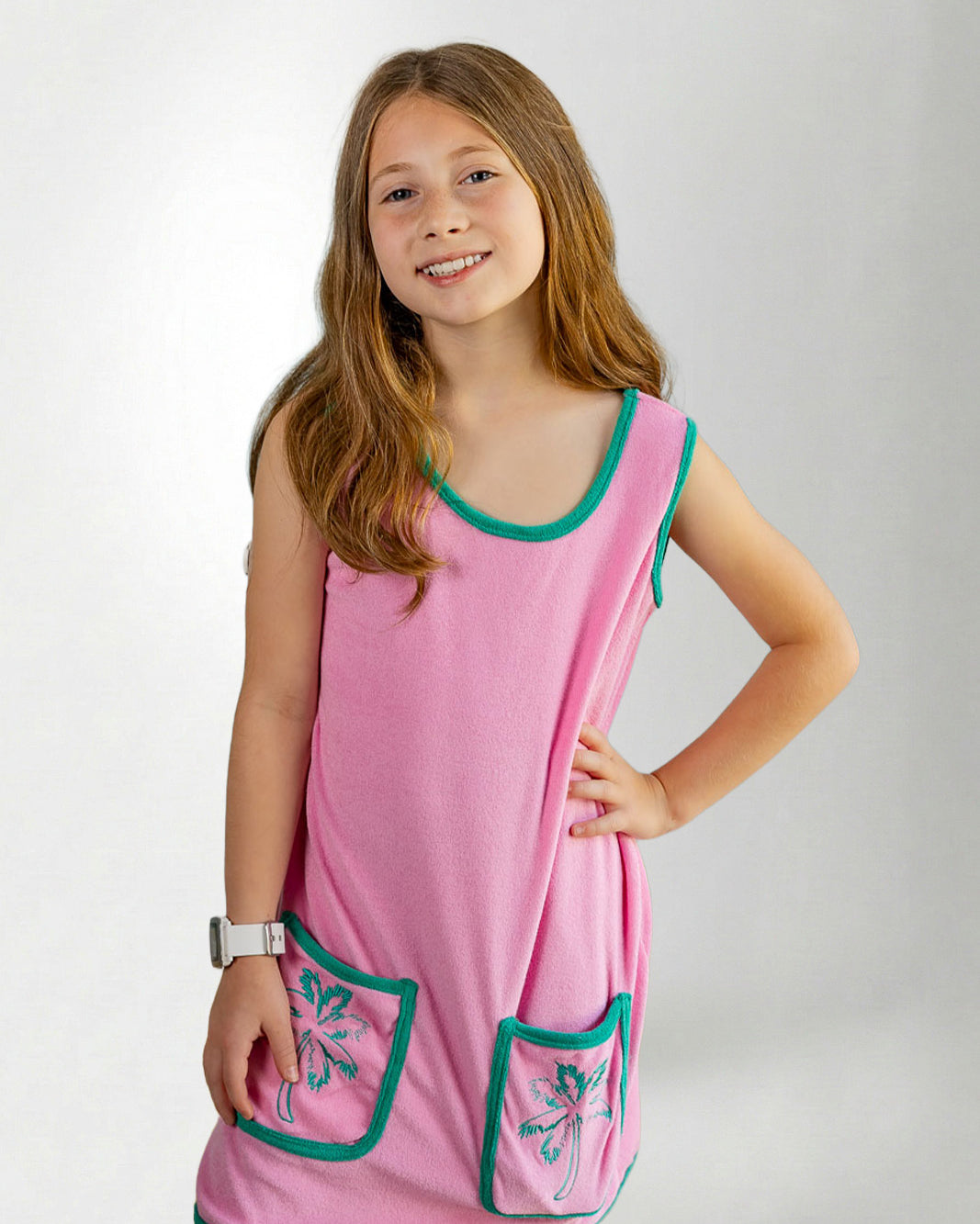 Young girl wearing a pink dress with green trim on a white background