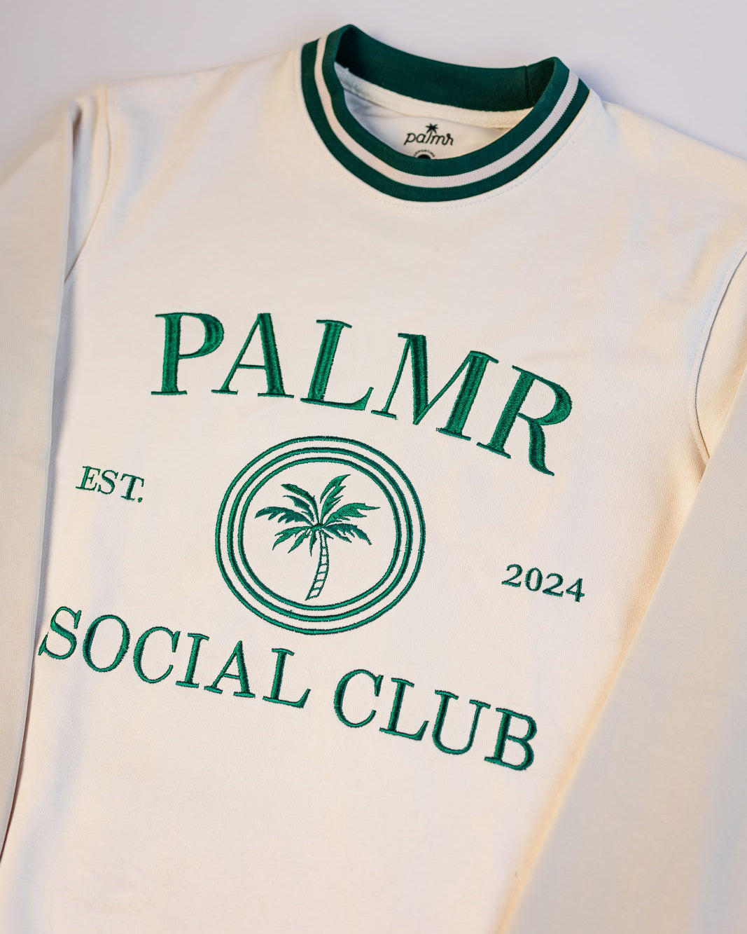 White sleeveless shirt with green text and palm tree design on a white background