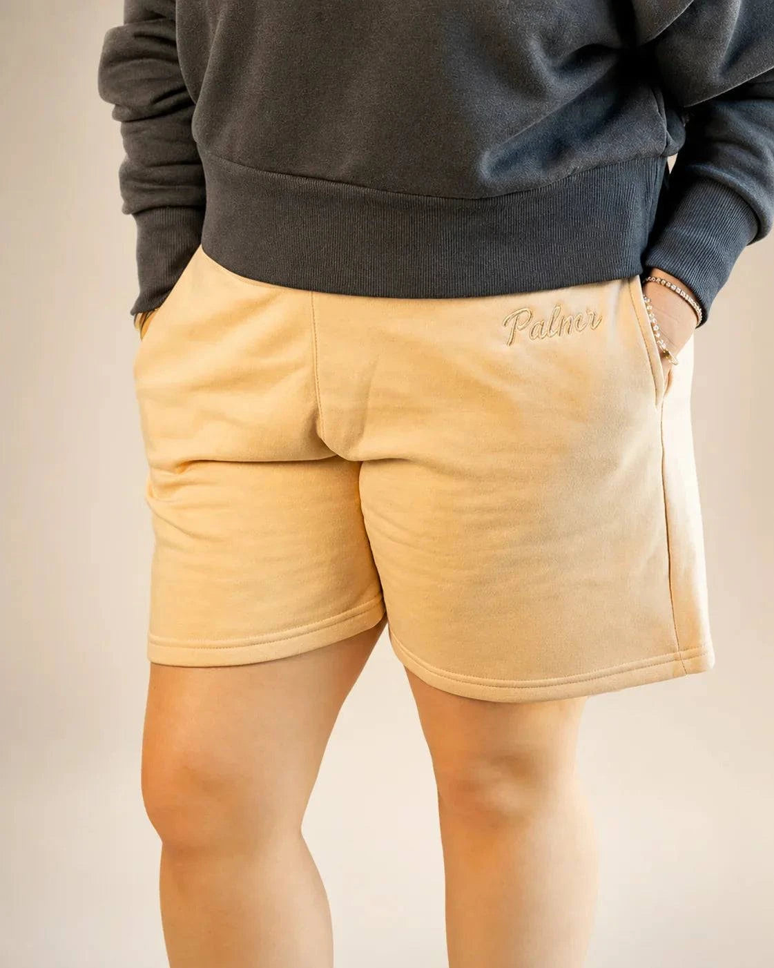 Cream Sandbar Fleece Shorts with high waist, elastic waistband, and side pockets featuring tonal Palmr logo