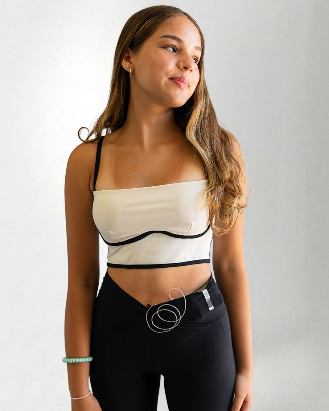 Woman wearing a white and black strapless top with black leggings on a plain background