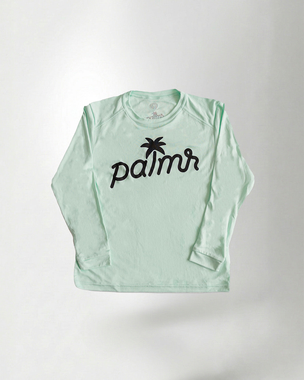 Light green long-sleeve shirt with 'palms' logo, colorful cap, sunglasses, and flamingo shorts on a white background.
