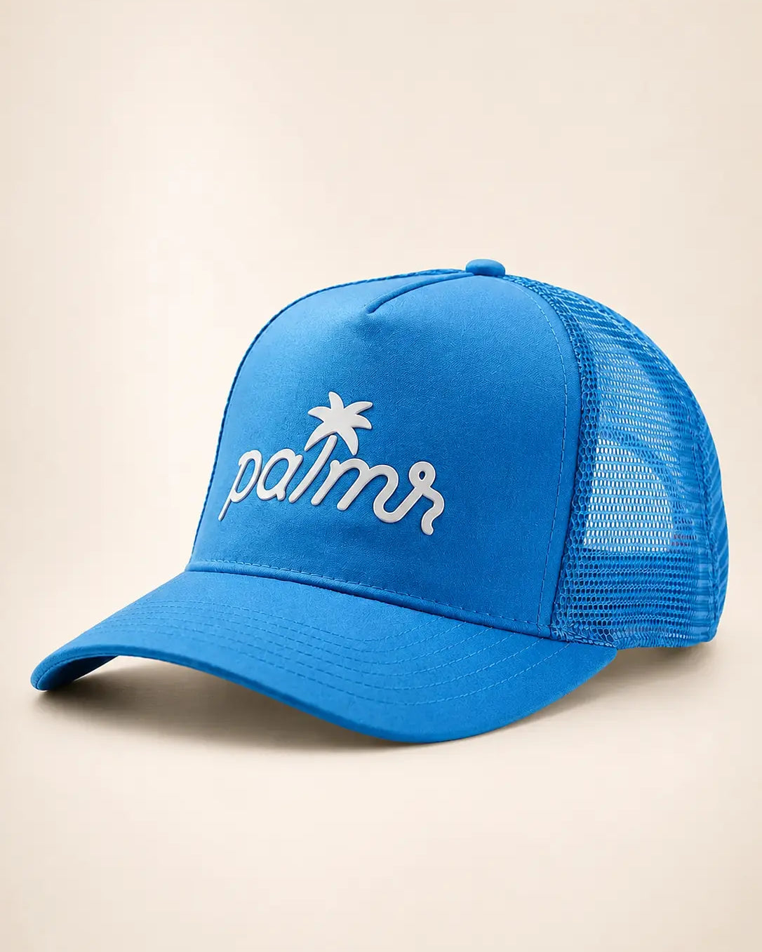 A bright blue trucker cap with white embroidered 'palmr' script and a palm tree logo on the front, set against a plain beige background.