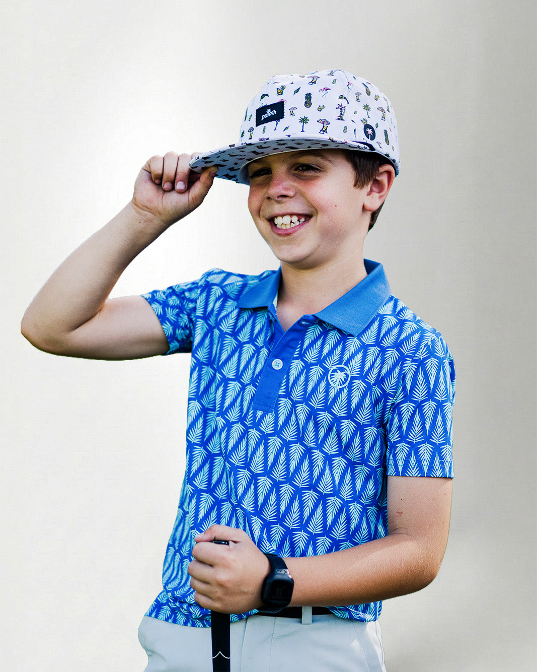 Child wearing a blue patterned polo shirt and cap with a white background