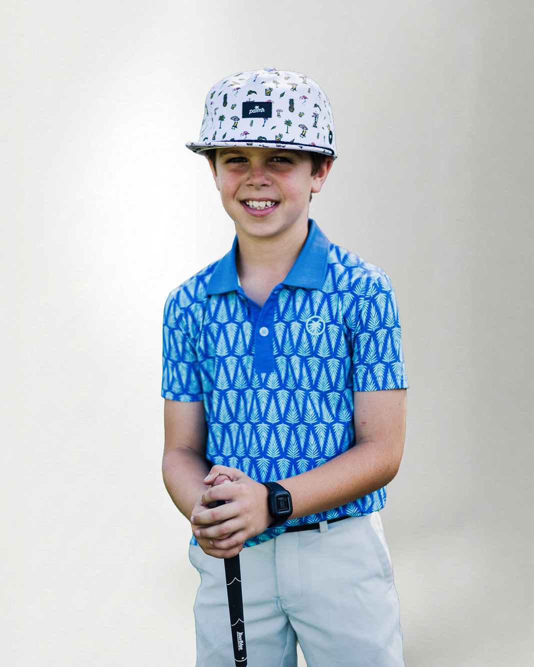 Child wearing a blue patterned polo shirt and cap with a white background