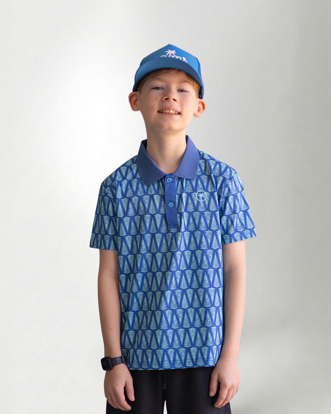 Child wearing a blue patterned polo shirt and cap with a white background
