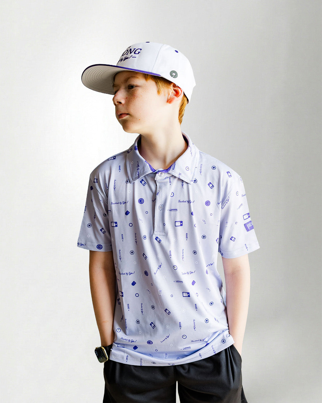 Child wearing a patterned polo shirt and cap on a plain background