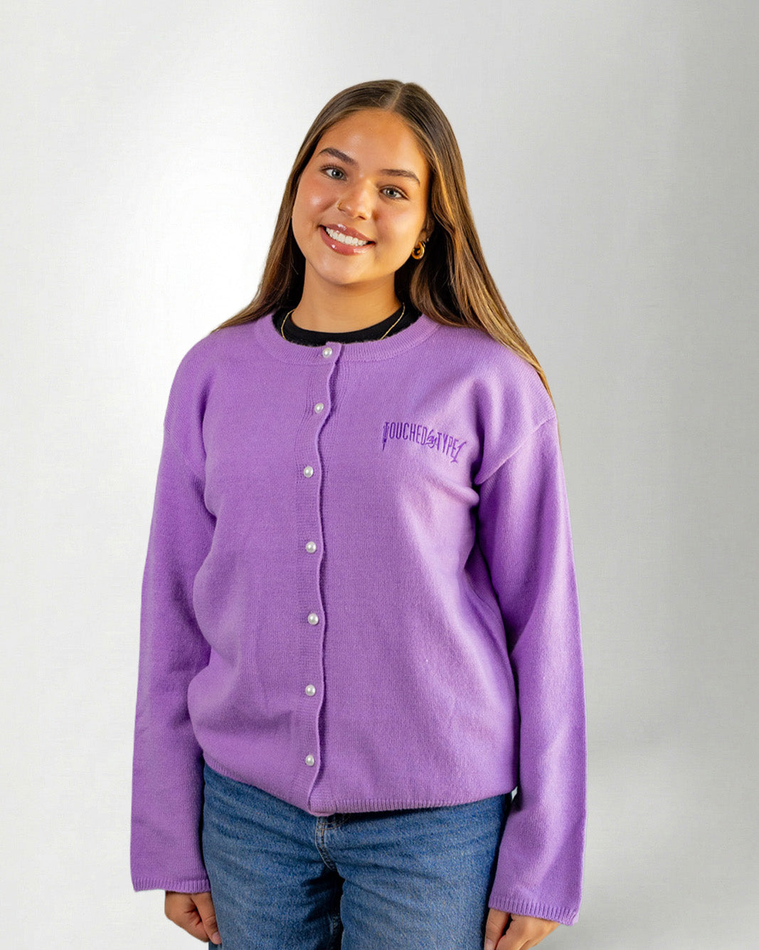 Woman wearing a Purple "Touched by Type 1" cardigan against gray background.