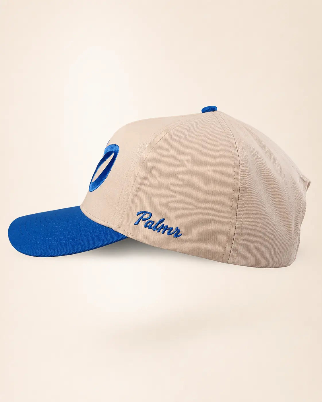 A beige baseball cap with a bright blue visor, blue button, and blue embroidered details, including the script text 'Palmr' on the side.