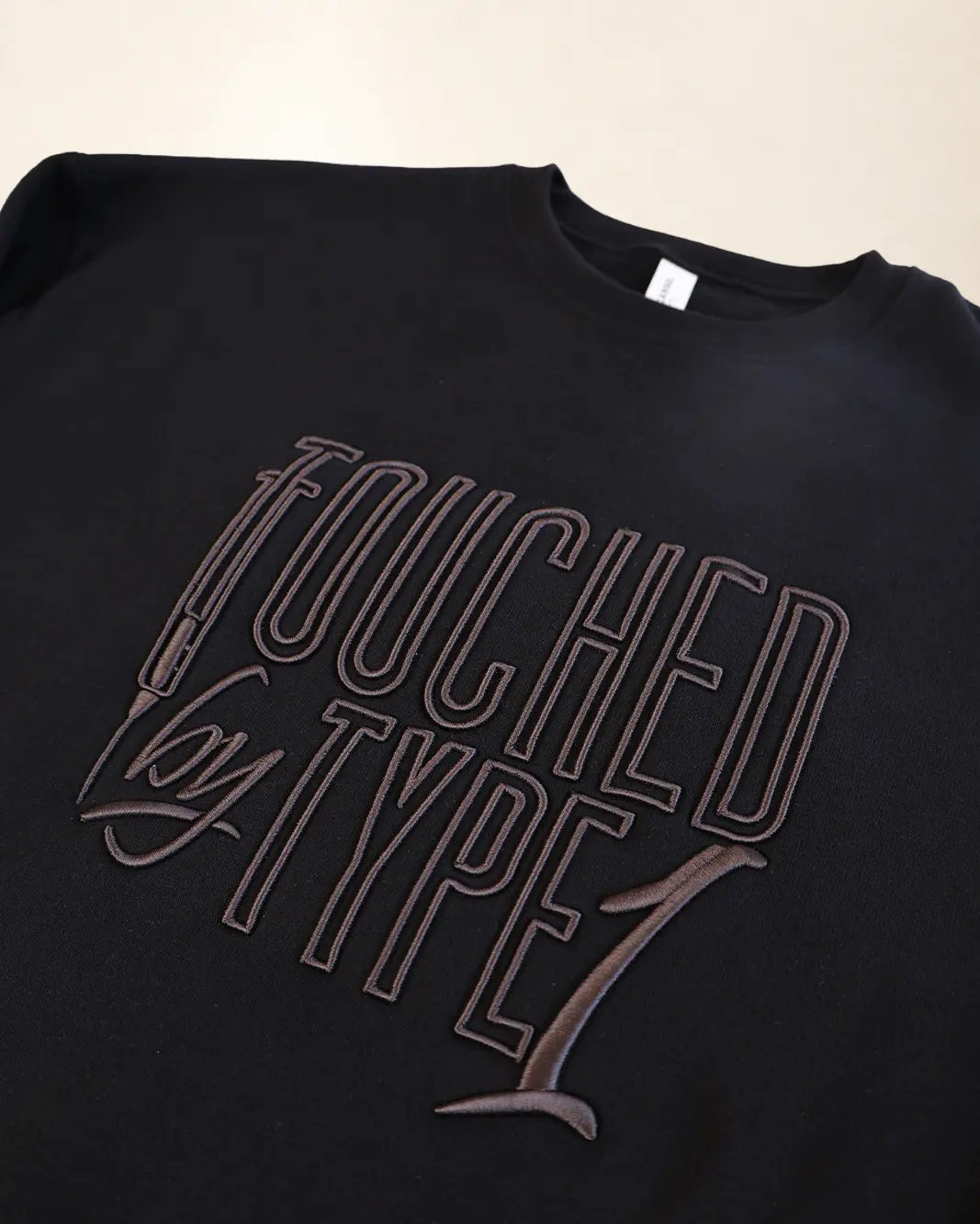 Black sweatshirt with 3d stylized embroidery lettering that says 'Touched By Type 1'