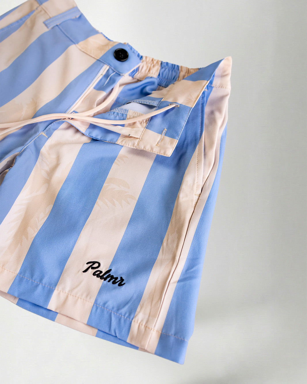 Person wearing striped shorts with "Palmr" embroidery