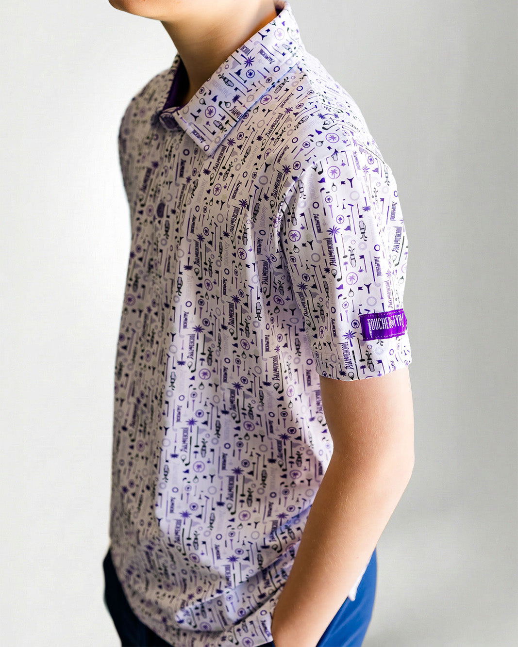 Child wearing a patterned shirt and blue cap against a plain background